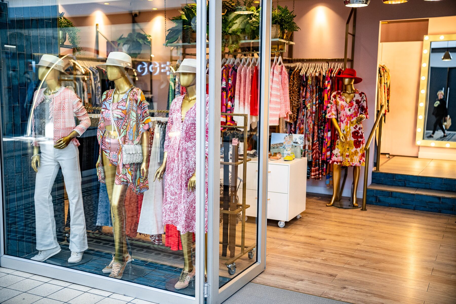 Gold mannequins presenting colourful fashion in a Colour Box window