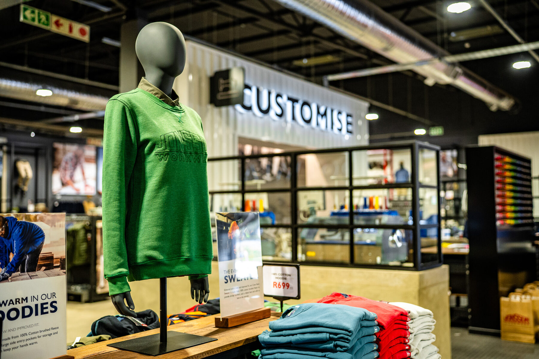 A black torso mannequin presenting a green Jonsson Workwear sweatshirt